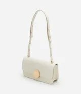 Cartera tipo shoulder bag de tamaño mediano, confeccionada en poliuretano color marrón oscuro. Presenta una solapa frontal con un detalle metálico dorado de forma orgánica y asa ajustable.