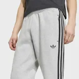Pantalón de jogging Adidas Spacer Teamgeist 26 Cutline Cuffed de color gris melange, con ajuste relajado, puños en los tobillos, las icónicas tres tiras de la marca en negro en los laterales y el logo del trifolio bordado.