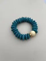 Set de tres pulseras elásticas con cuentas de madera en colores celeste, negro y rosa, con detalles de cuentas doradas y cuentas color crema.