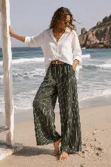 Pantalón de lino azul marino con finas rayas verticales blancas, de corte amplio y talle alto. Incluye bolsillos funcionales y una cintura elástica con cinturón de rafia desmontable.