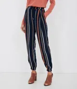 Pantalón de viscosa con rayas verticales en azul marino, blanco y naranja. Tiene bolsillos laterales, cintura elástica con cordón ajustable y tobillos ajustados con elástico.