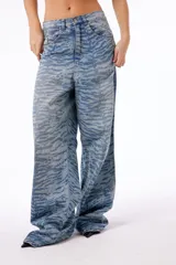 Pantalón jean oversized de tiro bajo, color azul lavado, con estampado de tigresa grabado con láser.
