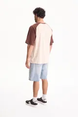 Remera oversize de manga corta raglán, color blanco con mangas y cuello en azul marino.