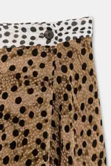 Falda midi de tiro alto con bajo asimétrico y cierre frontal cruzado con botón. Presenta un diseño que combina estampado de lunares y animal print.