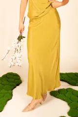 Falda larga de satén color verde mostaza, corte al bies, con caída fluida.