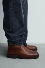 Bota de piel color marrón con cierre de cremallera lateral, horma cuadrada y suela con ligero tacón.