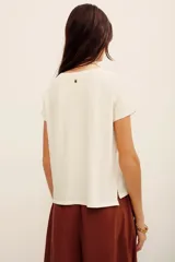 Remera blanca de algodón, de manga corta y corte recto, con estampa frontal que incluye un felino dorado rodeado de flores y la leyenda 'Stay Gold'.