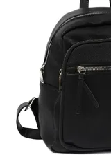 Mochila de cuero sintético color beige con textura granulada, cuenta con un compartimento principal con cierre, un bolsillo frontal con cierre y tirador decorativo, y asa superior.
