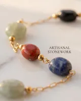Pulsera de cadena fina con baño de oro, adornada con tres piedras naturales de distintos colores y formas irregulares distribuidas a lo largo de la cadena.