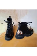 Borcego de cuero negro con cordones, suela de plataforma y detalles de arte pintado a mano en el talón.