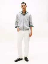 Buzo gris de felpa de algodón con capucha ajustable con cordón y cierre de cremallera frontal. Tiene dos bolsillos tipo canguro y logo de Tommy Hilfiger bordado en el pecho.