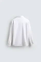 Camisa de corte regular fit confeccionada en popelín de algodón. Presenta cuello abotonado, manga larga con puños ajustables mediante botón y cierre frontal de botonadura completa.