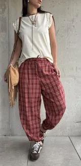 Pantalón estilo babucha color rojo con estampa a cuadros, tiro medio y cintura elástica con cordón ajustable.