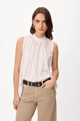 Blusa sin mangas color crema, con cuello alto fruncido y diseño holgado.