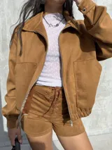 Campera de estilo bomber confeccionada en tejido tipo gamuza scuba, color marrón tostado. Presenta cierre frontal, cuello camisero, puños y ruedo elásticos, brindando un ajuste cómodo y versátil.