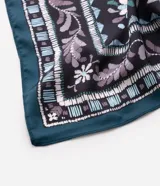 Pañuelo cuadrado confeccionado en satén con estampa paisley en tonos verde, violeta y negro, con marco ornamentado y acabado en los bordes.