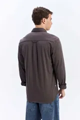 Camisa de manga larga color verde militar, con cuello tradicional y cierre frontal de botones.
