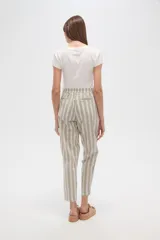 Pantalón tipo babucha de corte recto y tiro medio, con cintura elástica y cordón ajustable con borlas decorativas. Presenta un diseño de rayas verticales en tonos neutros.