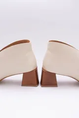 Botines de cuero color beige con diseño de tajo frontal, punta fina y taco cuadrado de madera.