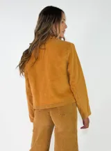 Chaqueta de pana color marrón, con solapas desflecadas, cierre frontal con botones y bolsillos delanteros con solapa desflecada.