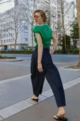 Pantalón tipo culotte de tiro alto confeccionado en denim azul oscuro. Presenta pinzas delanteras, pernera ancha y corta, bolsillos laterales ocultos y cierre frontal con cremallera, botón y ganchos.