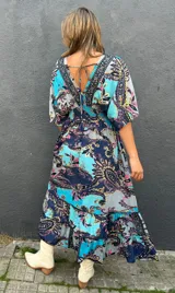 Vestido midi de seda con estampado paisley en tonos turquesa, azul marino, rosa y amarillo. Cuenta con mangas cortas fluidas y diseño amplio.