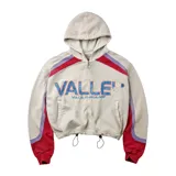 Campera con capucha de corte boxy, color blanco con detalles en rojo y lila en las mangas y hombros, cierre frontal completo y cordón ajustable en la cintura. Presenta la inscripción "VALLEY" y "VALE DREAMS" estampada en el frente.