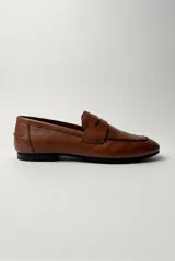 Mocasín de cuero color marrón, con diseño clásico tipo penny loafer y suela plana.