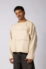 Buzo oversize de corte boxy, confeccionado en algodón rústico de alto gramaje en color beige. Presenta cuello redondo con borde crudo, mangas largas y una estampa frontal con el texto VCP delimitado por líneas horizontales blancas.