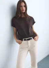 Jeans de tiro medio y corte recto de color marfil, con diseño crop y bajo deshilachado. Presenta cinco bolsillos, trabillas para cinturón y cierre frontal con cremallera y botón metálico.