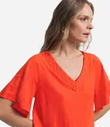 Blusa de manga corta color naranja, confeccionada en tejido Orly, con escote en V con detalle de costuras trabajadas.