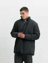 Campera de estilo Harrington en color verde oscuro, con cuello alto, cierre frontal y solapa con botones.