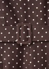 Mono enterito de lino color marrón con estampado de lunares blancos, cuello redondo, sin mangas, perneras rectas y cinturón integrado con hebilla a tono.