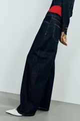 Jeans de tiro alto confeccionados en denim azul oscuro, con diseño barrel de pernera holgada que se estrecha hacia los tobillos. Cuenta con cinco bolsillos, trabillas para cinto y cierre frontal con cremallera y botón.