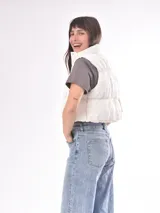 Chaleco negro con cuello alto y cierre frontal con botones a presión.