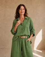 Camisa de lino verde oliva, de corte oversize y largo asimétrico, con cuello camisero, cierre frontal de botones, bolsillo aplicado en el pecho y mangas largas regulables con presilla.