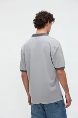 Remera polo de manga corta color rojo con efecto lavado, cuello y puños en contraste marrón. Cuenta con media cartera de botones, aberturas laterales en el dobladillo y un bordado pequeño de una estrella en el pecho.