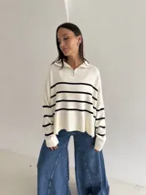 Sweater estilo chomba con cierre frontal, confeccionado en tejido bremer rayado de manga larga. Presenta un diseño amplio y moderno con cuello polo.