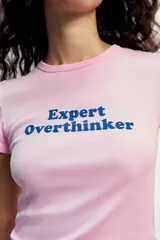Remera rosa de manga corta y cuello redondo, con el texto "Expert Overthinker" estampado en azul en el centro del pecho.