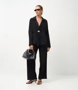 Pantalón de corte recto confeccionado en tejido satinado de viscosa y poliéster. Presenta pliegues delanteros marcados, cintura con trabillas y bolsillo trasero incorporado.