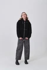 Campera de corderito color negro, con cuello alto y cierre frontal completo. Presenta detalles de vivos en cuero sintético en el cierre, bolsillos y costuras, además de una hebilla decorativa en el cuello.