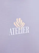 Camiseta lila de manga corta con estampado en la espalda de hojas y círculos en tonos blanco y naranja.