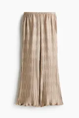 Pantalón wide leg de tejido plisado con ligero brillo, color beige, con cintura elástica y bolsillos laterales.