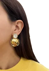 Aros colgantes dorados con un círculo superior blanco y un círculo inferior dorado con textura.