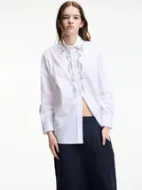 Camisa blanca de algodón con cuello camisero, cierre frontal con botones y apliques de pedrería en cuello y cartera de botones.