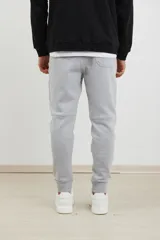 Pantalón jogging de corte slim, con puños elastizados, cintura con cordón ajustable, cierres laterales engomados y bolsillo tipo parche lateral.