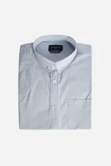 Camisa de manga corta Brooksfield, color celeste con textura de micro-rayas verticales. Presenta cuello abotonado, cierre frontal con botones y un bolsillo en el pecho con el logo de la marca bordado.