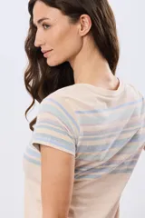 Remera de manga corta con cuello redondo, de color beige con diseño de franjas horizontales en tonos celestes y rosados en la parte superior.