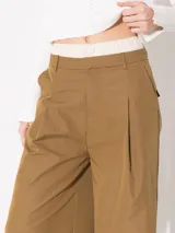 Pantalón negro de gabardina con pata ancha y doble cintura: una de tela base con gancho pantalonero y otra interna de poliéster con elástico y botón. Tiene bolsillos laterales.