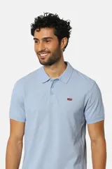 Chomba celeste de mangas cortas con cuello clásico y logo de la marca bordado en el pecho.